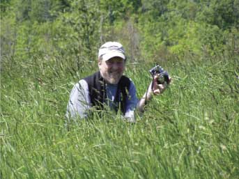 photograph of john copley, the artist, standing in a field with a camera